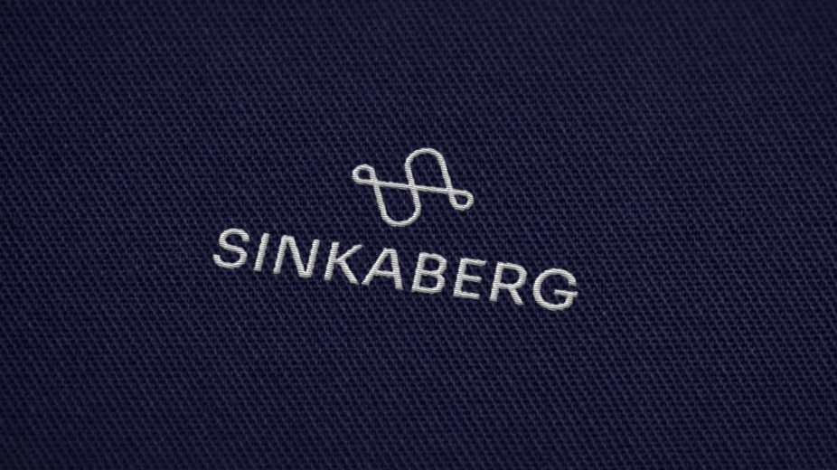 Sinkaberg logo brodert på blått stoff