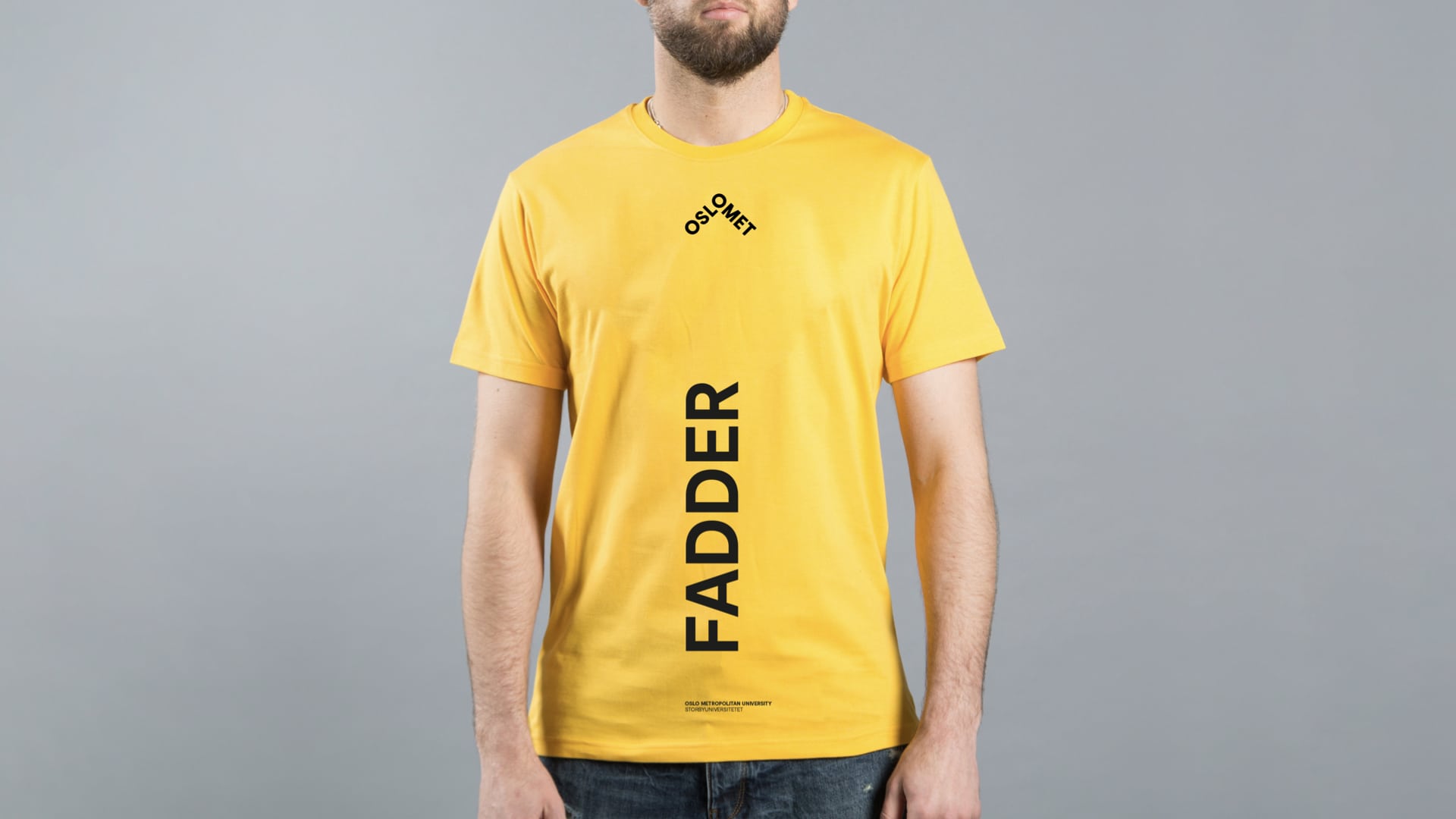 Mann med skjegg som har på seg en Oslo Met-gul t-skjorte hvor det står "fadder" vertikalt på midten.