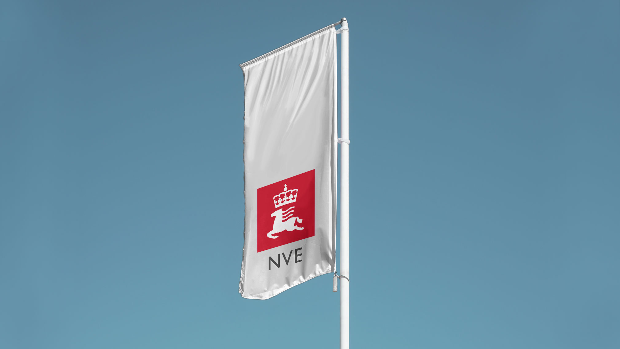 Foto av en flaggstang med et stort, hvitt, flagrende flagg med NVE sin logo i rødt og grått.