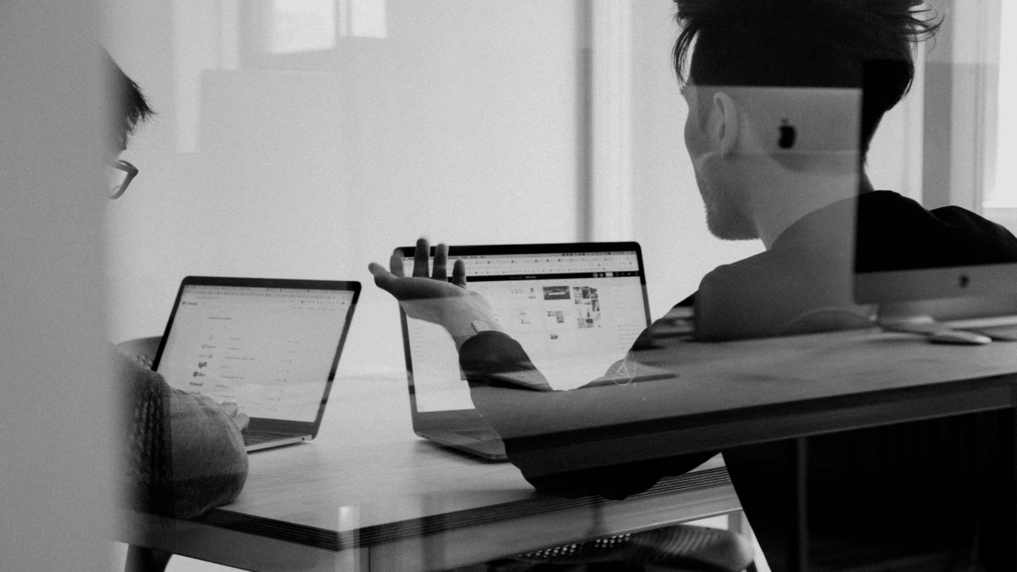 To personer sitter i et møterom og jobber, foran seg har begge hver sin laptop.