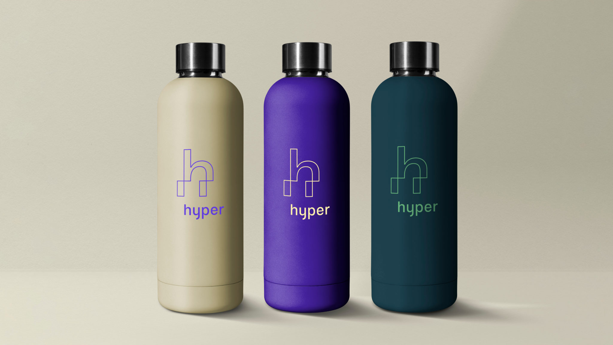 Foto av 3 drikkeflasker med reklamebyrået Hyper sin logo. Flaskene står på en beige bakgrunn og er i fargene beige, lilla og petroleumsblå.